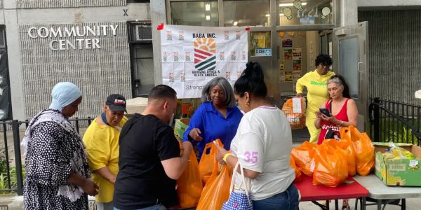 People distributing food bags outside a community center.