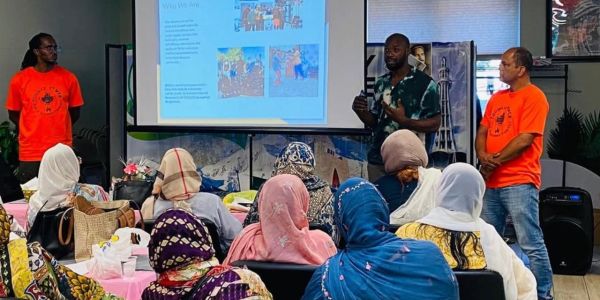 Community members attend a presentation by three men.