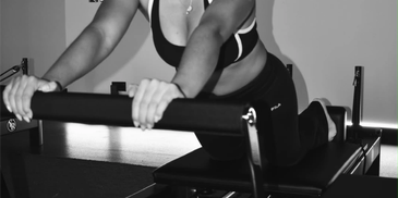 Person exercising on a Pilates reformer machine.