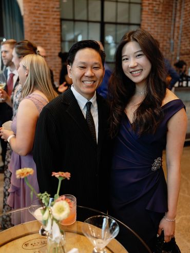 Guests smiling and socializing at an elegant corporate networking event inside a modern brick venue.