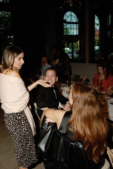 Guests laughing and chatting during an elegant dinner reception around candlelit tables with wine.