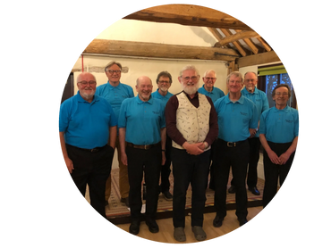 A group of elderly men posing indoors, most wearing matching blue polo shirts.