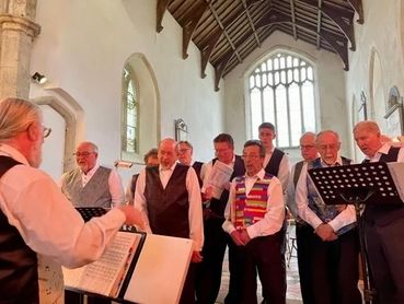 A group of men singing in a church choir led by a conductor.