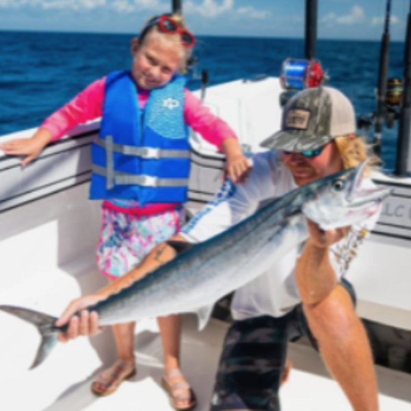 Man and child on a boat holding a large fish they caught.