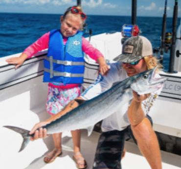 Man and child on a boat holding a large fish they caught.