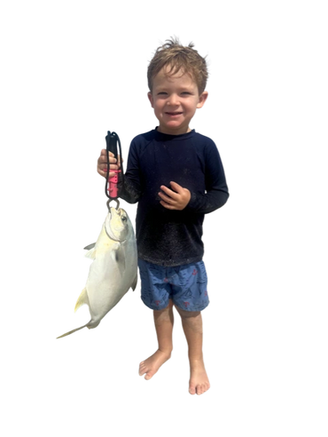 A young boy proudly holding a large fish he caught.