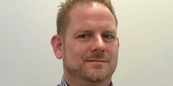 A man with short hair and a trimmed beard.