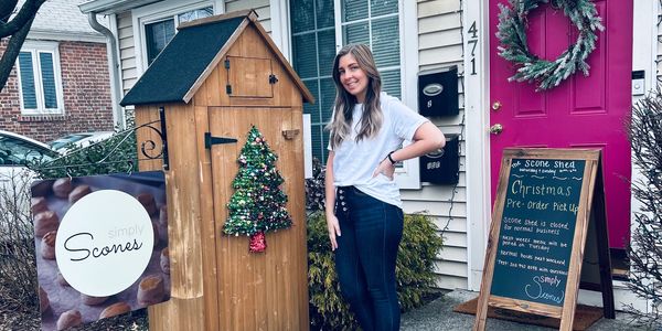 Woman standing outside Simply Scones shop decorated for Christmas.
