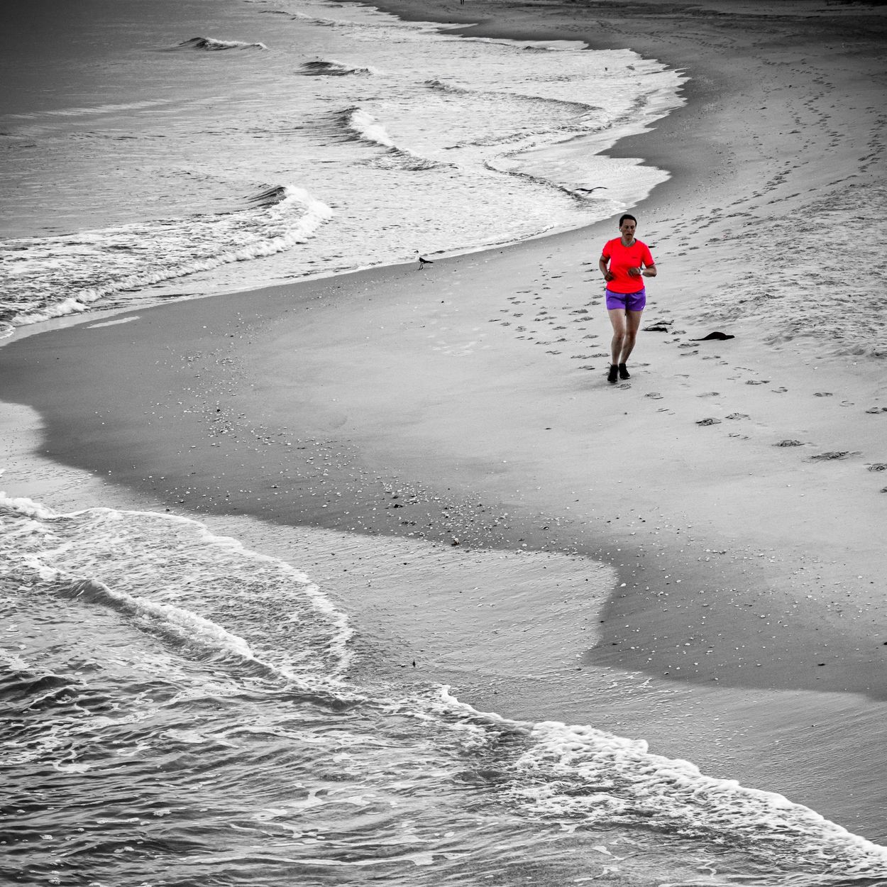 Colorful jogger on Naples Beach, partially converted to black and white.