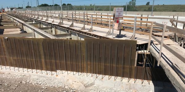 Construction site with wooden framework and metal reinforcements for a concrete structure.
