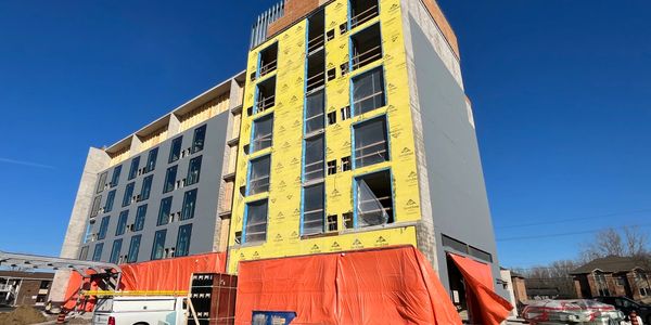A mid-construction multi-story building under a clear blue sky.
