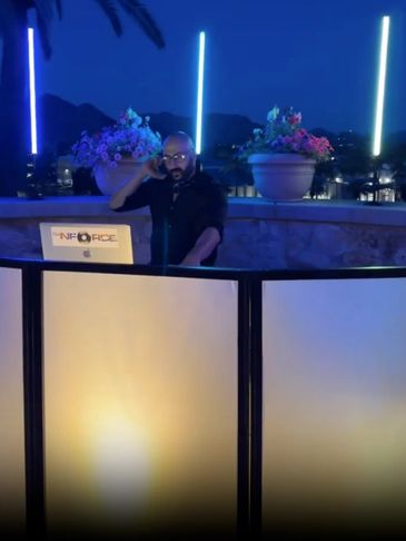 DJ performing at night with neon lights and floral decorations.