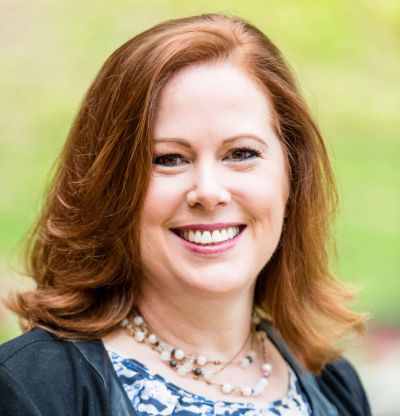 Smiling woman with red hair outdoors in natural light.