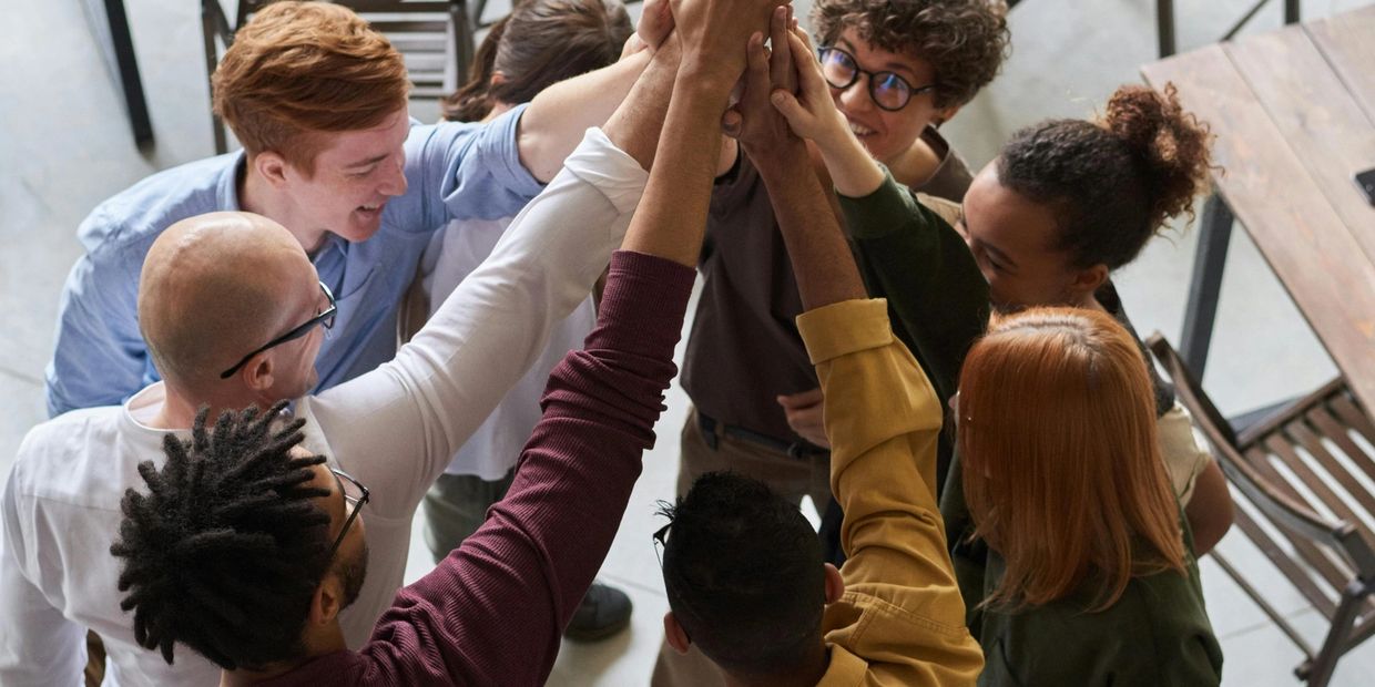 A diverse group of people joining hands in a team high-five.