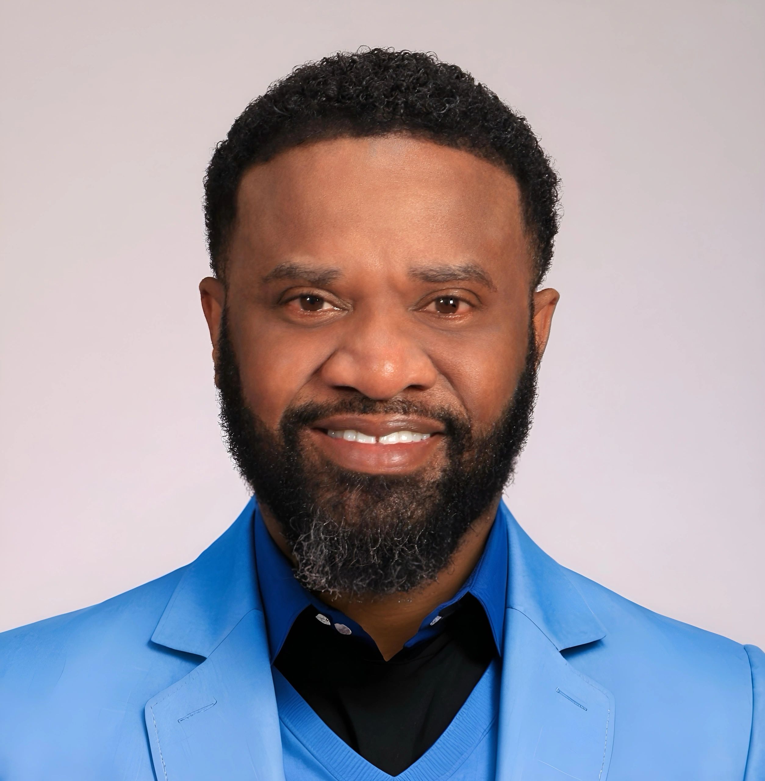 Smiling man in a blue suit against a plain background.