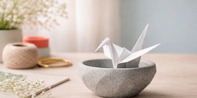An origami bird sat in a stone bowl to depict Good Egg's inspiration service