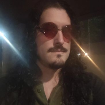 Person with long curly hair and round sunglasses at night.