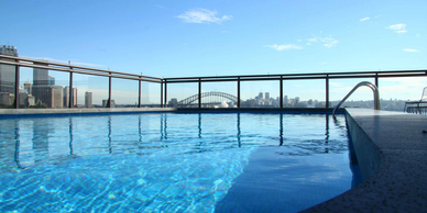 Rooftop pool with cityscape and bridge in the background.