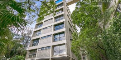 Tall concrete office building surrounded by trees.