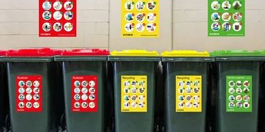 Recycling bins labeled for different waste types with matching posters above.