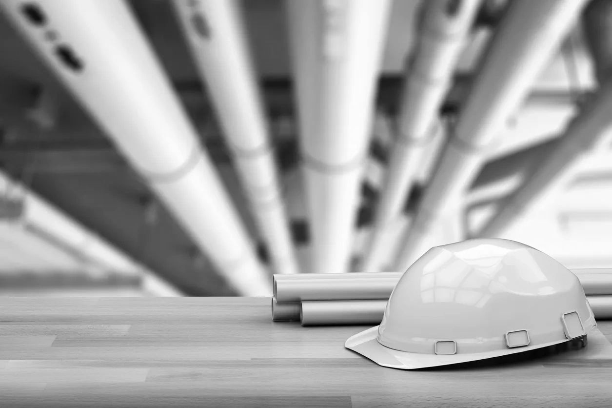 Wood table with rolled-up engineering drawings and a hard hat