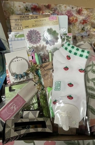Box filled with various accessories and craft items including socks, stickers, and jewelry.