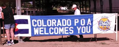 Club members putting up a banner at a show that says "Colorado POA Welcomes You."