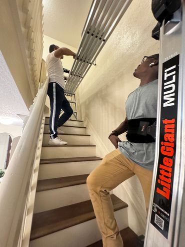 Two men installing or inspecting pipes on a staircase.