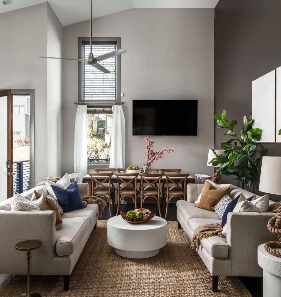 Cozy modern living room with two sofas, a round coffee table, and a dining area in the background.