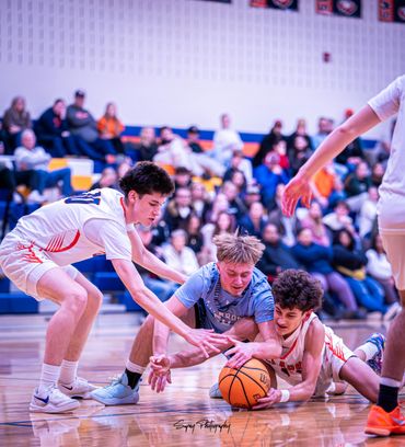 High school basketball players diving for the ball during an intense game.