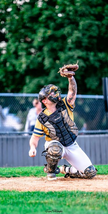 Baseball catcher in gear reaching up to catch a ball during a game.