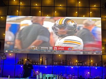 TV screen shows a college football game between Missouri and Kansas.