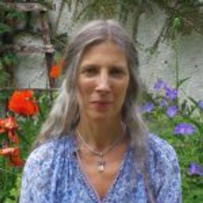 Woman with long gray hair in a floral garden.