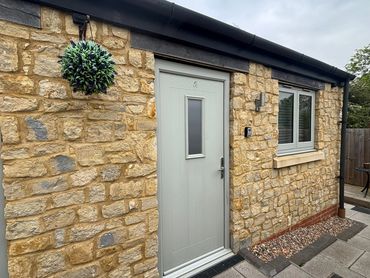 Stone house exterior with a light gray door and hanging plant.