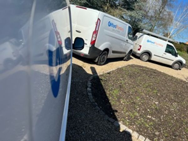White vans with company logo parked near a ranch
