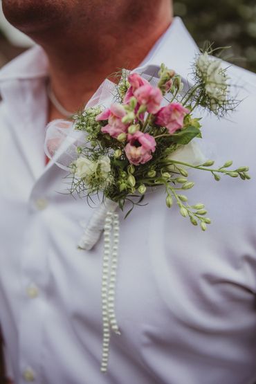 Custom boutonniere wrapped in rehire ribbon with pearls hanging down to match the bridal bouquet