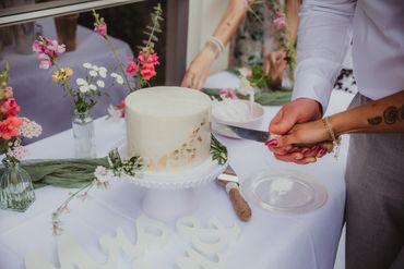 Bud vases on a table with a couple cutting a cake decorated in local floral
