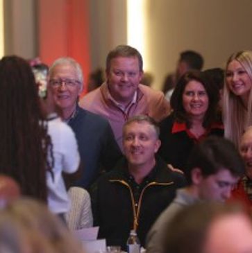A group of people smiling and posing for a photo at an indoor event.