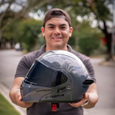 Hombre mostrando un casco gris para moto.