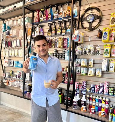 Hombre sonriente en tienda mostrando producto.