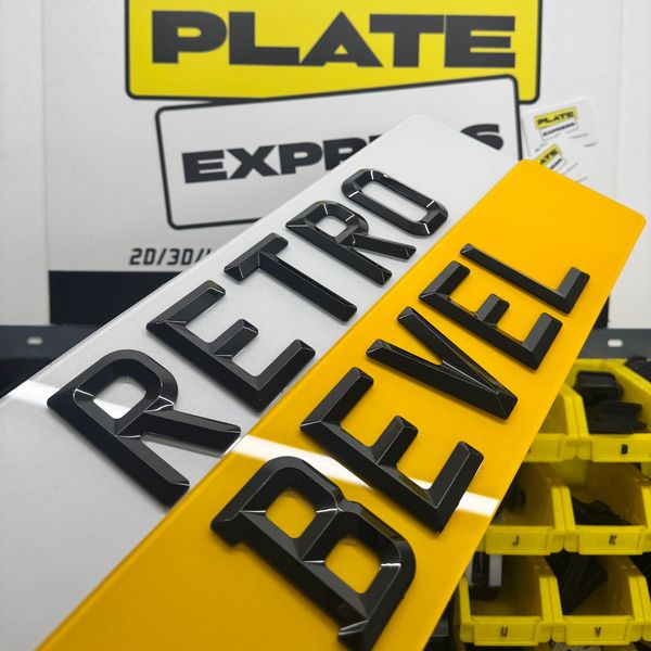 A close-up of a vehicle license plate with raised black letters on white and yellow background.