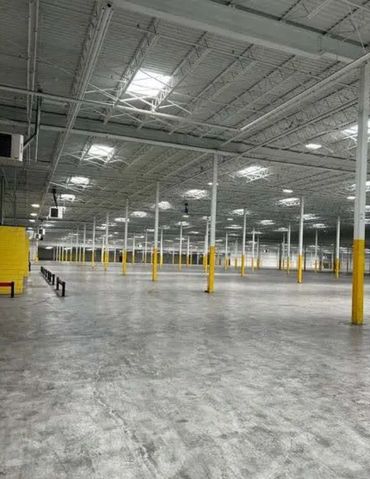 Large empty warehouse with yellow-striped pillars and concrete floor.