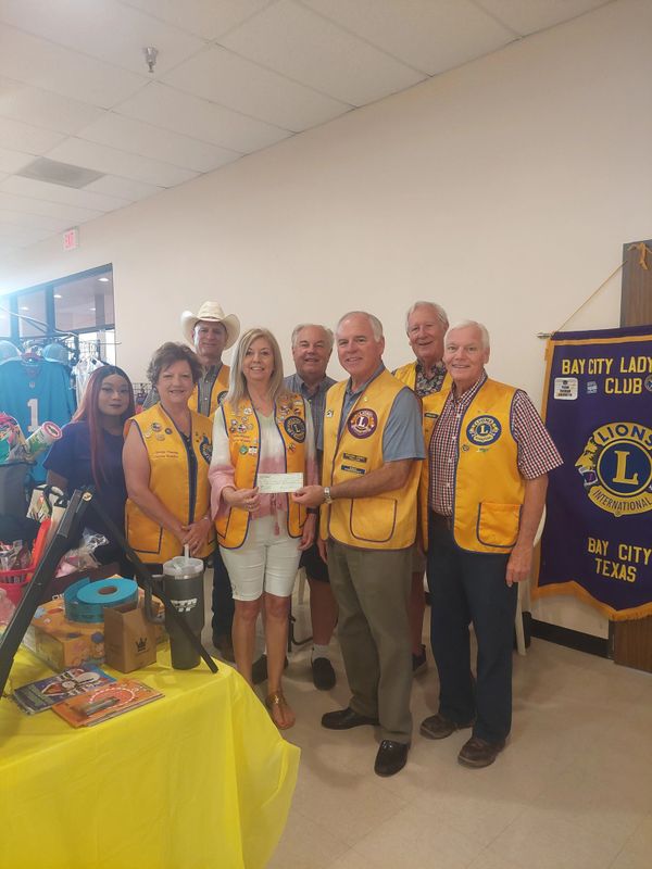 Members of Bay City Lions Club presenting a check indoors.