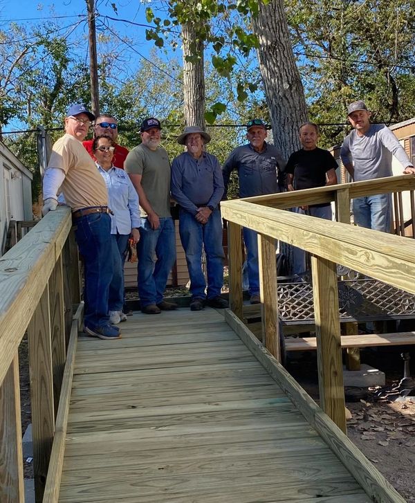 Group of eight people standing on a newly built wooden ramp outdoors.