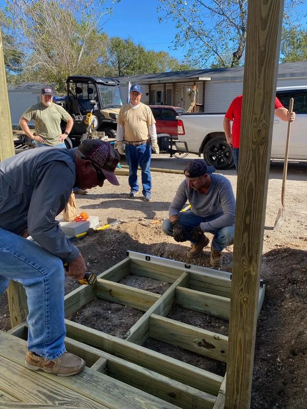Group of men building a wooden structure outdoors on a sunny day.