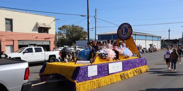 Children in formal attire ride a colorful Lions International parade float.