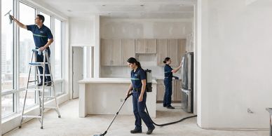 group of 3 cleaners cleaning a space post construction, they are wiping down appliances, windows and