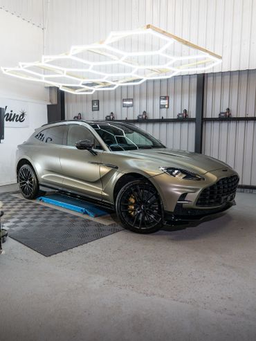 A sleek metallic SUV under hexagonal ceiling lights indoors.