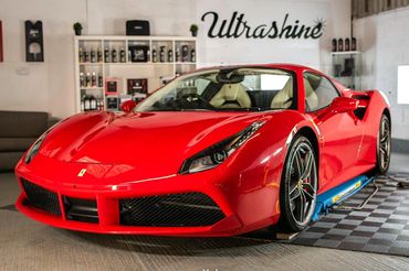 A shiny red Ferrari sports car parked indoors near Ultrashine products.