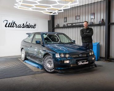 Man standing next to a shiny Ford car in a garage with Ultrashine branding.